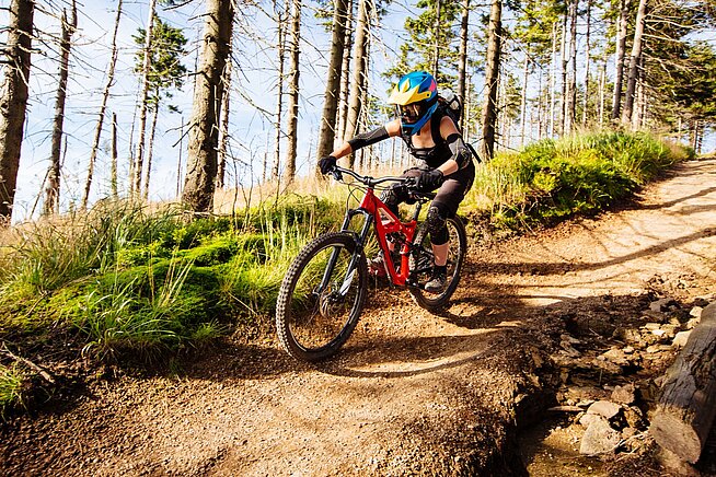 Mountainbiker fährt bergab über einen steilen Offroad-Trail im Wald