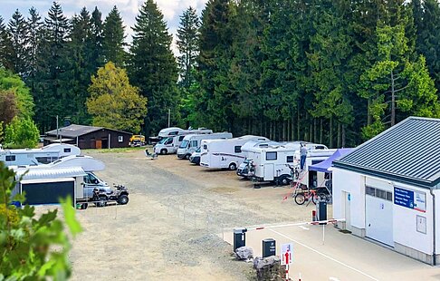 Wohnmobilstellplatz am Bikeverleih Schneider in Winterberg mit mehreren Campern und Wald im Hintergrund