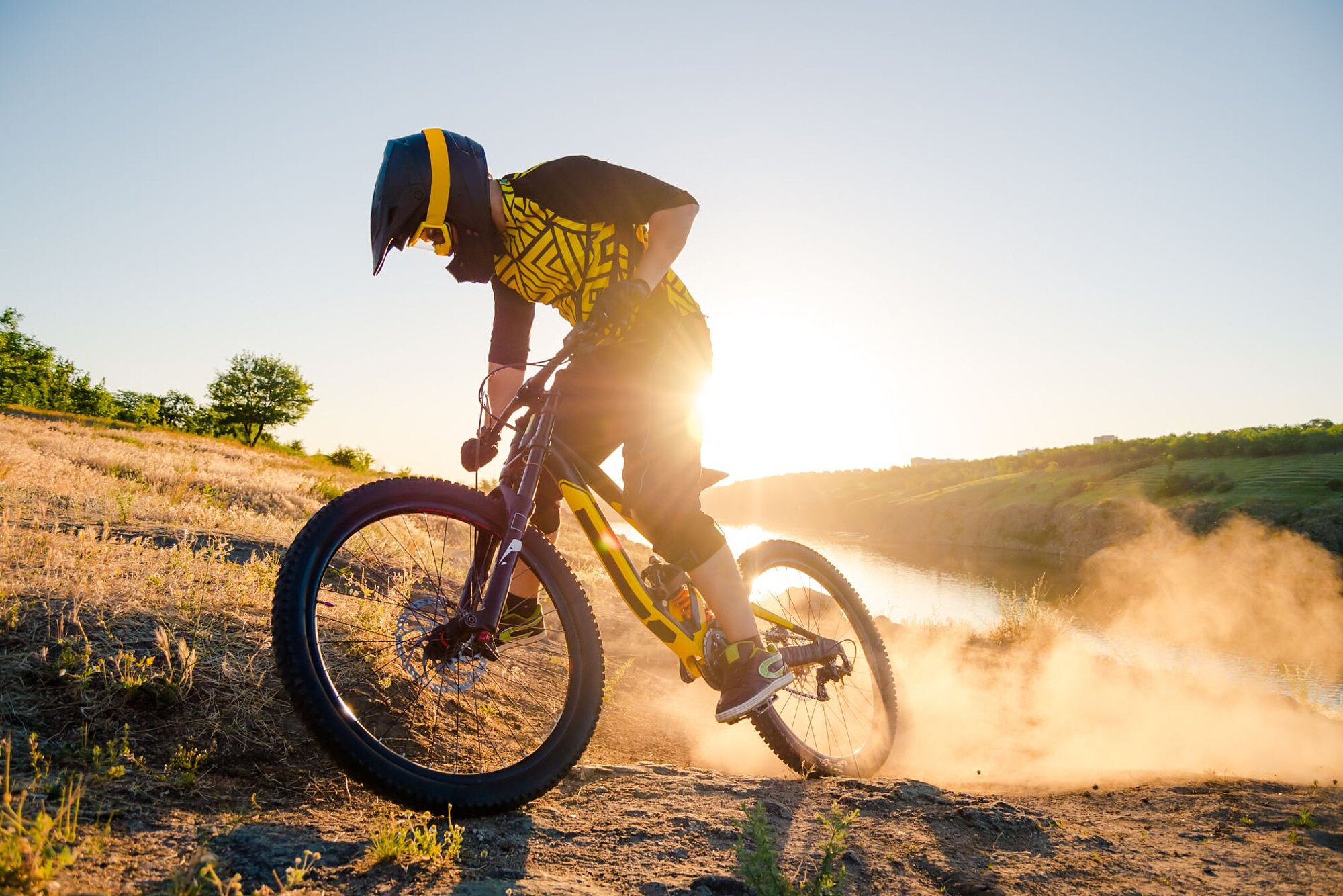 Mountainbiker driftet in Kurve und wirbelt Staub im Sonnenuntergang auf