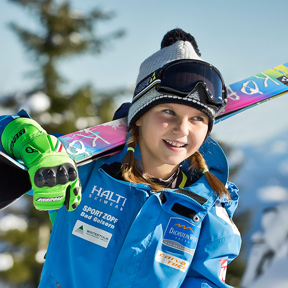 Zwei Kinder mit bunten Ski gehen durch verschneite Winterlandschaft